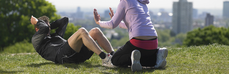 Woman helping man doing sit-ups