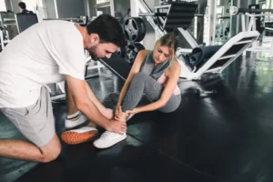 bastante-mujer-que-tiene-lesión-durante-ejercicio-en-gimnasio-mientras-sus-pares-toman-concepto-de-la-aptitud-los-primeros-143113125